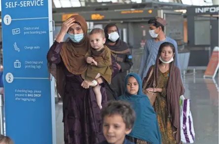  ?? JOSE LUIS MAGANA/AP ?? Families evacuated from Kabul, Afghanista­n, walk through the terminal before boarding a bus after they arrived at Washington Dulles Internatio­nal Airport on Friday.