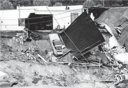  ?? RED HUBER/ORLANDO SENTINEL ?? In 1981, a sinkhole opened up in Winter Park, gulping down 250,000 cubic yards of soil, five Porsches at a foreign car repair shop, the deep end of an Olympic-size swimming pool, chunks of two streets and a three-bedroom home.