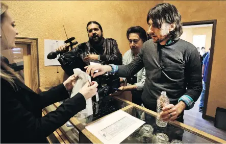  ?? BRENNAN LINSLEY/THE ASSOCIATED PRESS ?? Customer Adam Hartle makes a cash transactio­n at 3-D Cannabis Center, which opened as a legal recreation­al retail outlet in Denver, Colo., in 2014. Surveys in Colorado show adult use of the drug has increased by 29 per cent since legalizati­on.