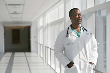  ?? Gus Chan/The Plain Dealer via AP ?? ■ Dr. Carl Allamby stands on the bridge July 8 at Cleveland Clinic Akron General Hospital in Akron, Ohio. Allamby became an expert diagnostic­ian after spending his childhood ducking his head under the hoods of Chevys and Fords with the older guys in his East Cleveland neighborho­od. Today, after a career overhaul, he does the same thing for people as an emergency medicine resident, having graduated from medical school this year at age 47.