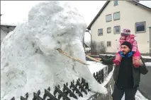  ?? THOMAS WARNACK / DPA VIA AFP ?? A man and a child look at an elephant made of snow and wooden sticks in Duernau, Germany, on Feb 23.