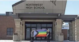  ?? MCKENNA LAMOREE/THE INDEPENDEN­T VIA AP ?? Former Saga staff members Marcus Pennell, left, and Emma Smith display a pride flag outside the school July 20.