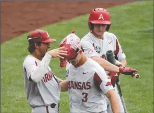  ?? The Associated Press ?? OPENING THE GATES: Arkansas’ Jared Gates (3) is greeted at the dugout by Hunter Wilson, left, and Jax Biggers after he hit a solo home run against Texas Tech in the second inning of an NCAA College World Series game in Omaha, Neb., Wednesday. The Razorbacks defeated the Red Raiders, 7-4.