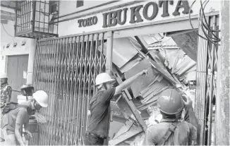  ?? AP-Yonhap ?? Workers inspect a store damaged during an earthquake in Cianjur, West Java, Indonesia, Monday.