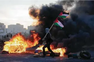  ?? Nasser Nasser / Associated Press ?? A Palestinia­n protester clashes with Israeli troops in the West Bank city of Ramallah following protests against President Donald Trump’s decision to recognize Jerusalem as the capital of Israel.