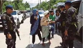  ??  ?? Policemen checking evacuees from Marawi aboard a van at a checkpoint near the entrance of Iligan City yesterday.