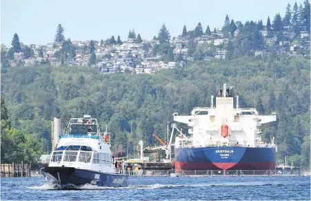  ??  ?? A Port Authority vessel patrols Burrard Inlet Tuesday as an oil tanker docks at Kinder Morgan’s Trans Mountain marine terminal in Burnaby.