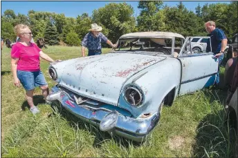  ??  ?? Richard Schulz (center), his wife, Joan, along with auctioneer Joe Aschoff (right) look over a 1953 Lincoln Cosmopolit­an.