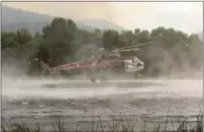  ?? DAViD ROyAl/tHe MONteRey COUNty HeRAlD ViA AP ?? A helicopter fills up with water from a pond at Rancho San Carlos before heading off to fight a wildfire in Carmel Valley, Calif., Wednesday. Acting Gov. tom torlakson, substituti­ng for Gov. Jerry Brown who is at the Democratic National Convention with...