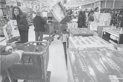  ?? AP Photo/John Minchillo ?? ■ Shoppers wait in line for iPhone purchases during a Black Friday sale on Friday at a Target store in Newport, Ky. Black Friday has morphed from a single day, when people got up early to score door busters, into a whole month of deals.