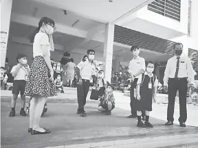  ??  ?? PANTAU: Guru Besar SJK (C) Yue Min Penampang Koh Chin Leung (kanan) turut memantau proses kawalan murid di sekolahnya.