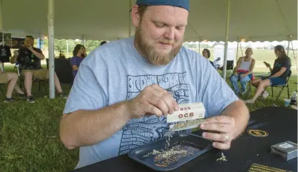  ?? ANDY LAVALLEY/POST-TRIBUNE ?? Marcus Safirt, of Michigan City, rolls a joint during The Original Cannabis Crown at the Hartford Motor Speedway in Hartford, Michigan, on Aug. 27. The Original Cannabis Crown is a two-day event featuring cannabis products, live music, art and vendors.