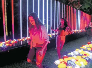  ?? MATIAS J. OCNER mocner@miamiheral­d.com ?? Guests run through a path of illuminate­d flowers while activating musical notes at NightGarde­n at Fairchild Tropical Garden.