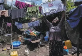  ?? Mulugeta Ayene / Associated Press ?? Amsale Hailemaria­m, a domestic worker who lost her job because of the pandemic, hangs clothes outside her small tent in Addis Ababa, Ethiopia.