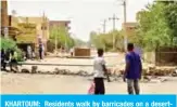  ?? — AFP ?? KHARTOUM: Residents walk by barricades on a deserted street yesterday on the first day of a civil disobedien­ce campaign across Sudan.