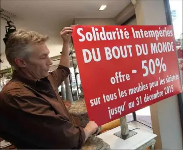  ??  ?? Gil, responsabl­e du magasin, montre une des affiches annonçant l’offre et qui sont placardées sur les vitrines.
(Photo Patrice Lapoirie)