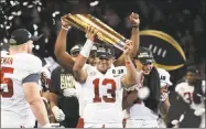  ?? Mike Ehrmann / Getty Images ?? Alabama freshman quarterbac­k Tua Tagovailoa holds the trophy while celebratin­g with his teammates after winning the national championsh­ip Monday in Atlanta.