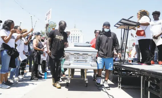  ?? Nina Riggio / The Chronicle ?? Participan­ts carry a coffin to represent people killed by gun violence in the city during the policeorga­nized “Stand Up for a Safe Oakland” antiviolen­ce rally.