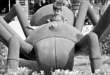  ??  ?? A Cambodian boy sitting on a tarantula statue at Skun town in Kampong Cham province.