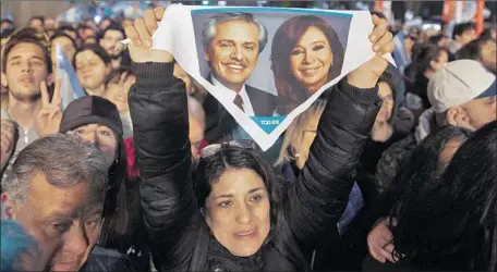  ?? Tomas F. Cuesta Associated Press ?? A SUPPORTER in Buenos Aires holds a small banner showing Alberto Fernandez and Cristina Fernandez de Kirchner after the primary.