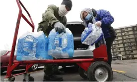  ?? Photograph: Paul Sancya/AP ?? Rabbi Yosef Chesed, left, helps unload bottled water being donated by Lorie Lutz, right, at a Detroit food pantry in March.