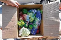  ?? Charlie Neibergall / Associated Press ?? A volunteer shows food to be donated at a produce giveaway organized by a Des Moines, Iowa, food pantry on Aug. 28. Across the country, people have picked up 75 million food boxes.