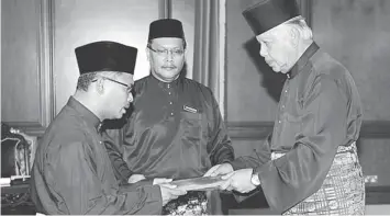  ??  ?? NEW CM: Khalil Yaakob (right) hands over the appointmen­t letter to Idris. — Bernama photo
