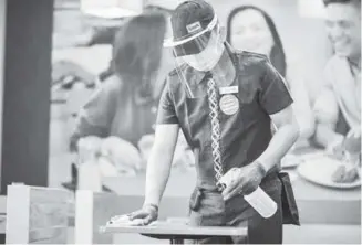  ?? PHOTOGRAPH­S COURTESY OF MANG INASAL ?? Plastic barriers are placed on tables for dine-in customers (above) while restaurant staff must wear gloves and face shield as well as constantly sanitize the dining area (right).