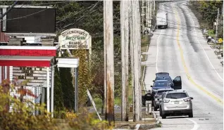  ?? NEW YORK TIMES ?? Officers gather at Schemengee­s Bar & Grill on Thursday after Wednesday night’s mass shooting there. Police in Maine were hunting for a gunman suspected of killing at least 18 people.