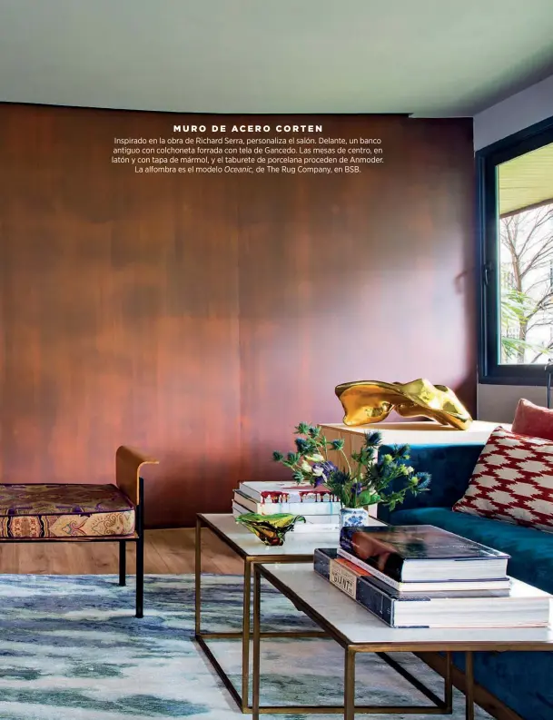  ??  ?? MURO DE ACERO CORTEN
Inspirado en la obra de Richard Serra, personaliz­a el salón. Delante, un banco antiguo con colchoneta forrada con tela de Gancedo. Las mesas de centro, en latón y con tapa de mármol, y el taburete de porcelana proceden de Anmoder. La alfombra es el modelo Oceanic, de The Rug Company, en BSB.