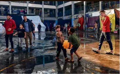  ?? ID KHATIB/AFP VIA GETTY IMAGES ?? Two boys carried a jerrycan through a yard at a school run by the United Nations Relief and Works Agency for Palestine Refugees in the southern Gaza Strip on Nov. 14.