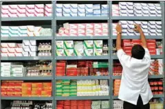  ?? MANJUNATH KIRAN/AFP ?? An Indian pharmacist pulls out a box of medicine from a shelf at a drug store in Bangalore.