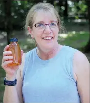  ??  ?? Paskiewicz holds a bottle of honey from her bees. (NWA Democrat-Gazette/Janelle Jessen)