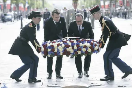  ??  ?? French President-elect Emmanuel Macron and outgoing French President Francois Hollande lay a wreath at the Tomb of the Unknown Soldier during a ceremony Monday marking the 72nd anniversar­y of the end of World War II at the Arc de Triomphe in Paris. Mr....