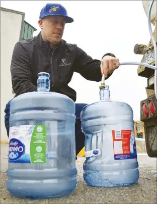  ?? JOE FRIES/Penticton Herald ?? Brent Hayter fills water jugs Sunday outside the Summerland aquatic centre. Like many residents, he had nothing but praise for the way the district handled a complex weekend repair job to the municipal water system.