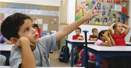 ??  ?? A FIRST-GRADER raises his hand in a classroom in the southern community of Nitzan.