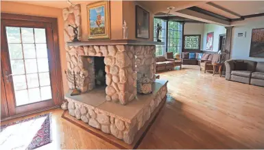  ?? JOHN KLEIN / FOR THE MILWAUKEE JOURNAL SENTINEL ?? A three-sided stone fireplace is a focal point in the home’s great room. The room has floor-to-ceiling windows that look out over the wooded shore of Lake Michigan.