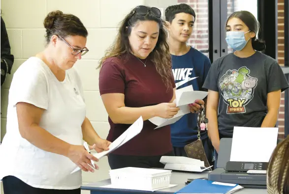  ?? JOHN SMIERCIAK/POST-TRIBUNE PHOTOS ?? Aidaleen Cortes, center, signs in her children Daniel Rivas 12, and Anjalise Rivas with registered nurse Sarah Lahey during a vaccinatio­n clinic put on by the Indiana Immunizati­on Coalition at Merrillvil­le High School on Thursday.