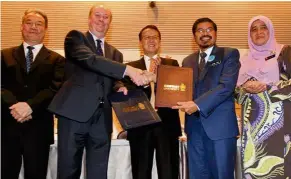  ??  ?? Prof Graeme Wilkinson (second from left) and Dr Mohd Uzir exchanging documents at the ceremony. Looking on are (from left) Prof Pua, Dr Cheah and Nazaria .