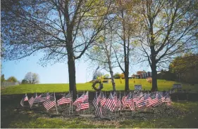  ?? BRIAN SNYDER / REUTERS ?? U.S. flags are planted outside the Holyoke Soldiers' Home in May for the veteran residents who died during a COVID outbreak at the facility.