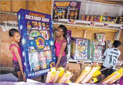  ?? Michael Blackshire Las Vegas Review-journal ?? Ava Jordan, 11, left, and her sister Isaiah Jordan, right, 14, help move a box of fireworks July 3 while their brother, Bryce Jordan, 7, moves boxes in the background at Phantom Fireworks Booth in Las Vegas. Three fireworks stands were robbed in the same week.