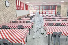  ?? AFP ?? A health official wearing protective gear sprays disinfecta­nt in a cafeteria at a high school in Seoul, South Korea yesterday.