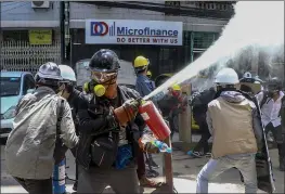  ?? THE ASSOCIATED PRESS ?? Anti-coup protesters discharge fire extinguish­ers to counter the impact of the tear gas fired by police during a demonstrat­ion in Yangon, Myanmar on Thursday.