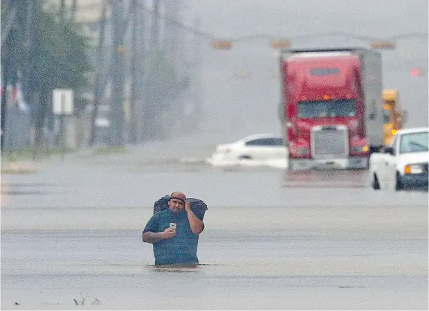  ?? THOMAS B. SHEA / AFP / GETTY IMAGES ?? A man walks through flood waters in Houston, Texas, on Sunday, as the fourth-largest U. S. city is pummelled by what remains of Hurricane Harvey.