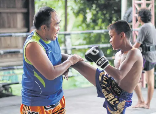  ??  ?? GETTING THEIR KICKS: Pol Sen Sgt Maj Piroj Chansod, a former profession­al muay Thai fighter and police officer who trains kids at Wor Watthana gym.