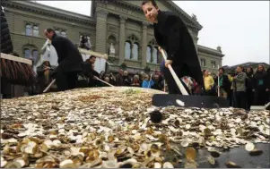  ??  ?? Swiss backers of a minimum universal income spread out coins at a recent rally in Bern. A whopping 76 per cent of voters were against the proposal.