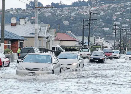  ??  ?? Cars plough through flooded roads in Dunedin as the city tried to cope with a one-in-a-100 year flood.