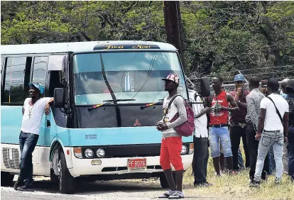  ?? NORMAN GRINDLEY ?? Police search passengers from this bus at a checkpoint in the St Catherine North Police Division’s state of public emergency.