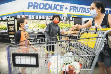  ?? Santiago Mejia / The Chronicle ?? BARGAIN HUNTING: Jacob Barajas, 9, brother Abram, 11, and mother Paulina Barajas shop at FoodMaxx in Concord. Barajas, with five children and her husband’s hours cut, has switched from shopping at big-brand supermarke­ts to discount stores to save money.