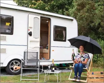  ??  ?? SOCIAL BUBBLES: Caravan fan Caroline Howes celebrates with champagne in the rain